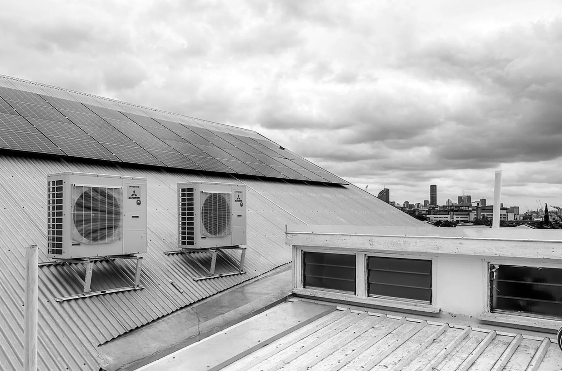 Mitsubishi outdoor air conditioning units on a roof with the Brisbane skyline behind